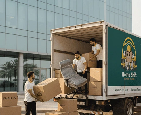 Professional office movers loading furniture and packed boxes into a moving truck in Dubai.